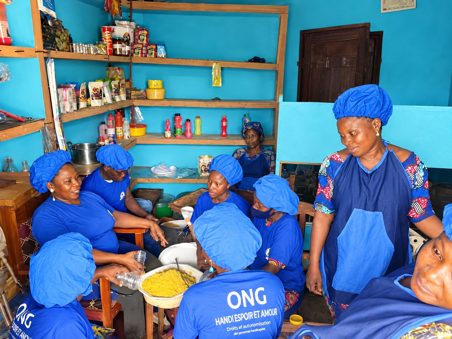 Les membres de l'atelier, en tee-shirt et charlotte bleus de l'ONG, préparent ensemble des produits dans la boutique