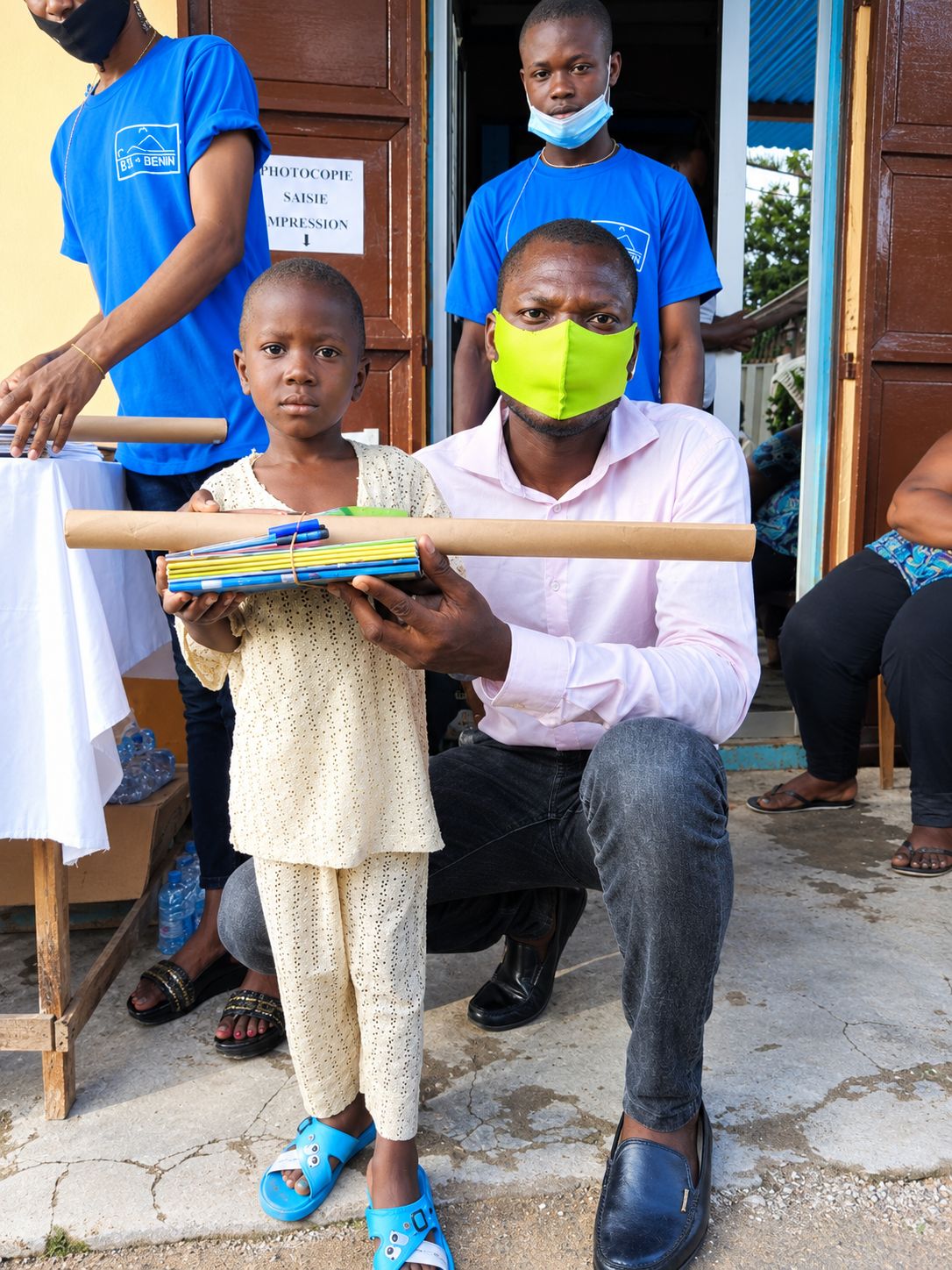 Un enfant reçoit ses fournitures scolaires des mains d'un membre de l'ONG