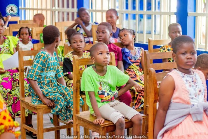 Des enfants assis attendent la remise des kits