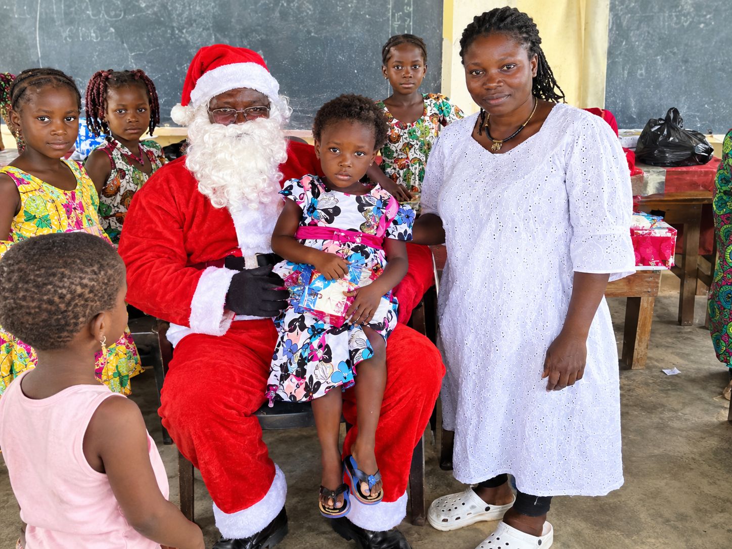 Le Père Noël et une membre de l'ONG offrent des cadeaux à des enfants